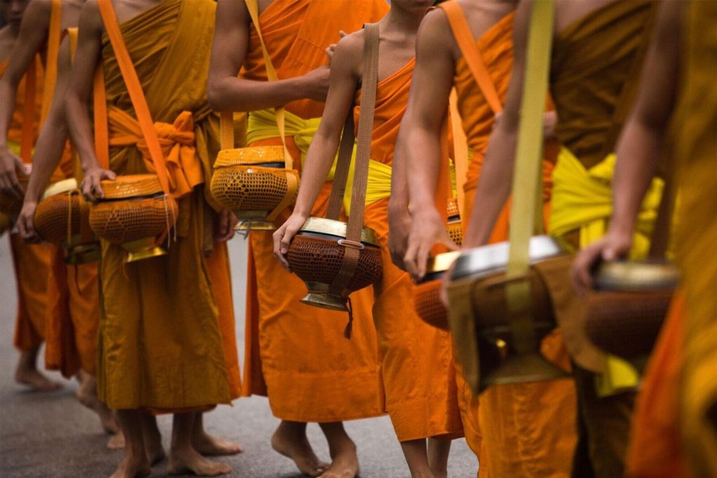 Buddhist monks in saffron robes walking in a traditional alms-giving procession, showcasing cultural rituals and spiritual experiences as meaningful Things to Do in Cambodia.